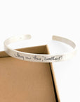 Silver bracelet with engraved text on a white background