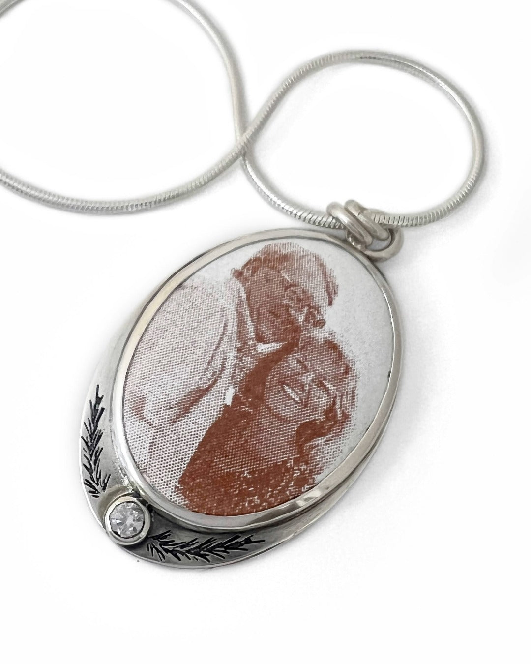 Silver pendant with a vintage-style portrait on a white background