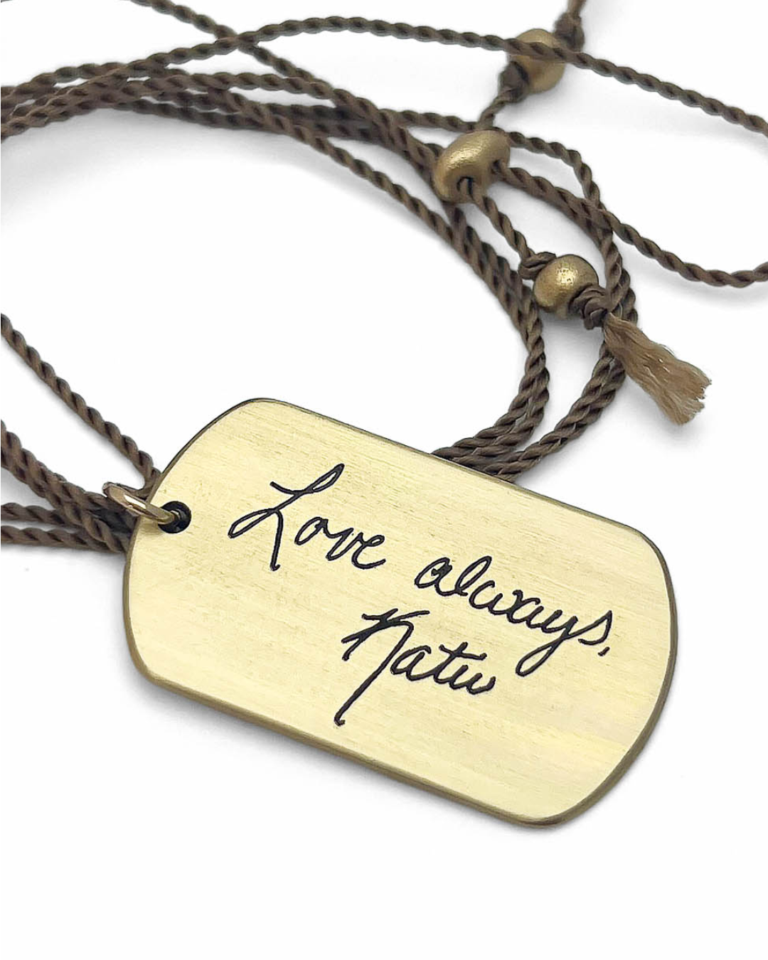 Gold toned pendant with 'Love always, Katie' engraved in handwriting - on a braided cord.