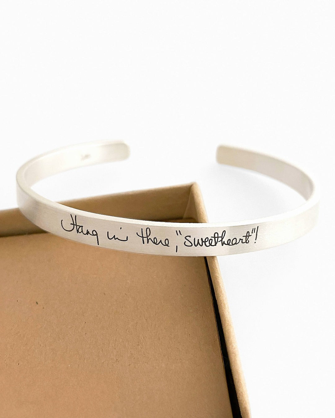Silver bracelet with engraved text on a white background