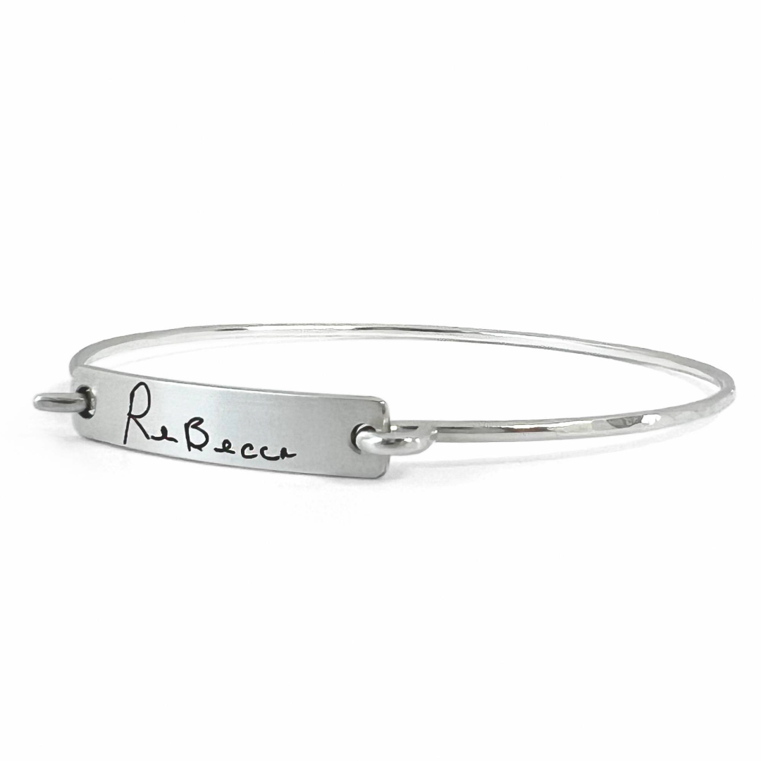 Silver bangle with engraved name 'Rebecca' on a white background