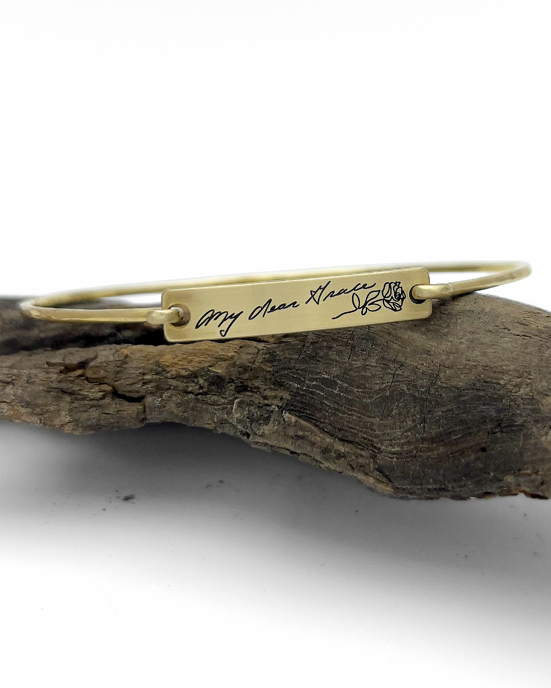 Gold bracelet with engraved text on a piece of wood