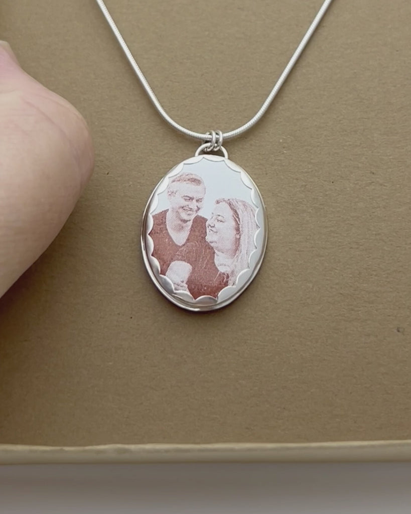 Memorial pendant with enameled photograph and wildflower engraving in a kraft gift box. 