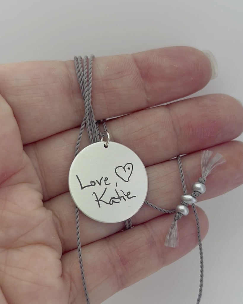 Large round silver pendant engraved with handwriting. Modeled and moving. 