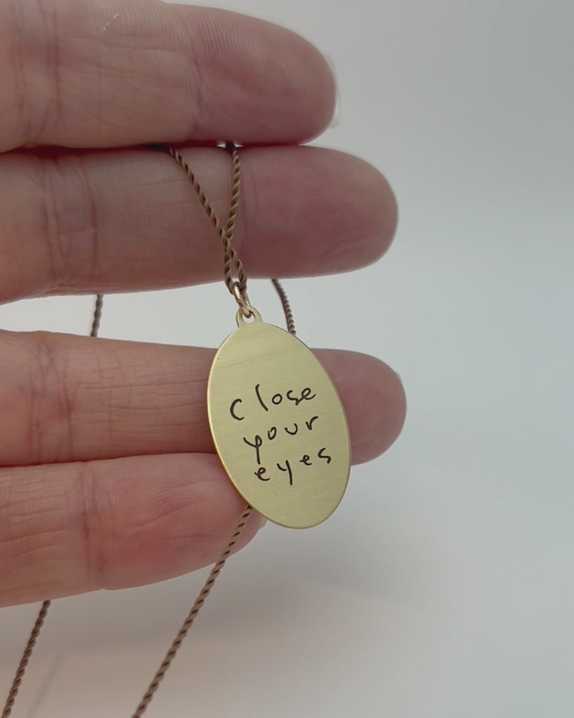 Brass pendant with embossed star motif and handwriting engraved on the back.