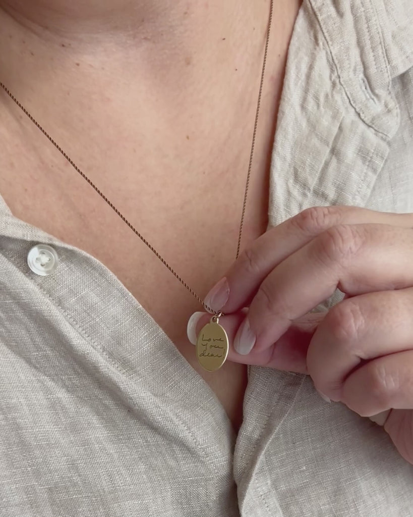 Small gold pendant engraved with "Love you dear" in the client's own handwriting. 