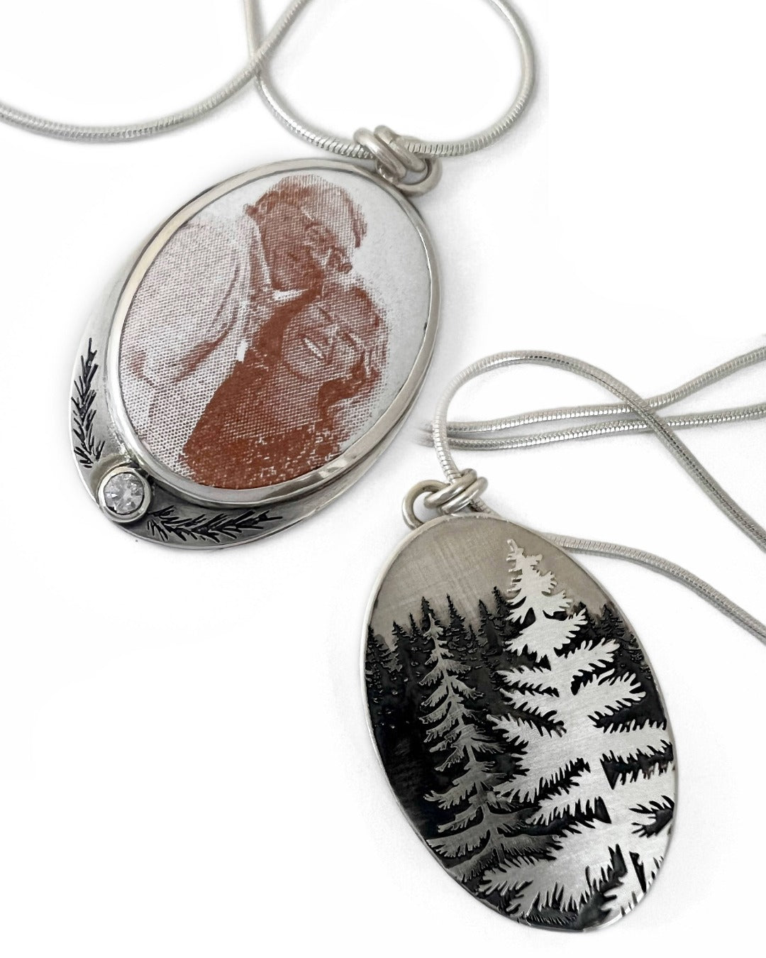 Two oval pendants on a white background, one with a nature design and the other with a portrait.